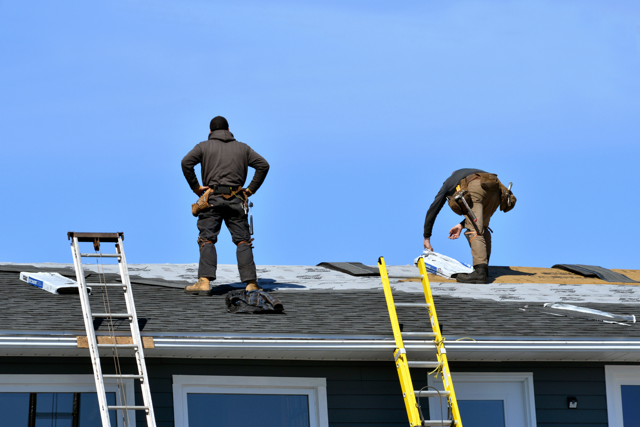 Two Men Roofing a House in the Sunshine