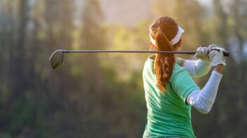 Sport Healthy. Asian sporty woman golf player doing golf swing tee off on the green sunset evening time, she presumably does exercise. Healthy and Lifestyle Concept.