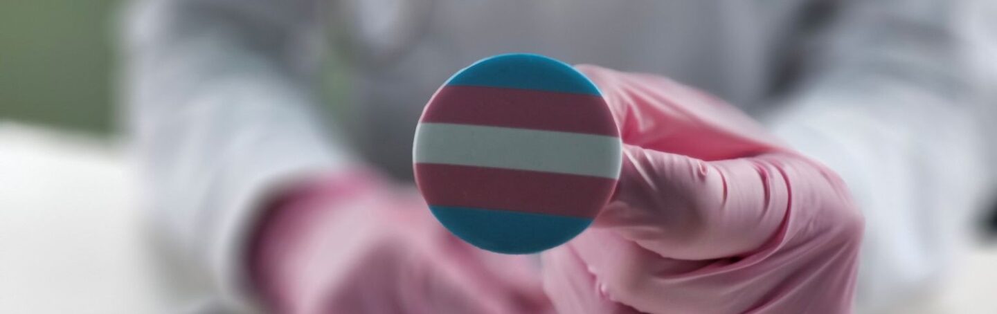 Doctor holding a transgender flag pin