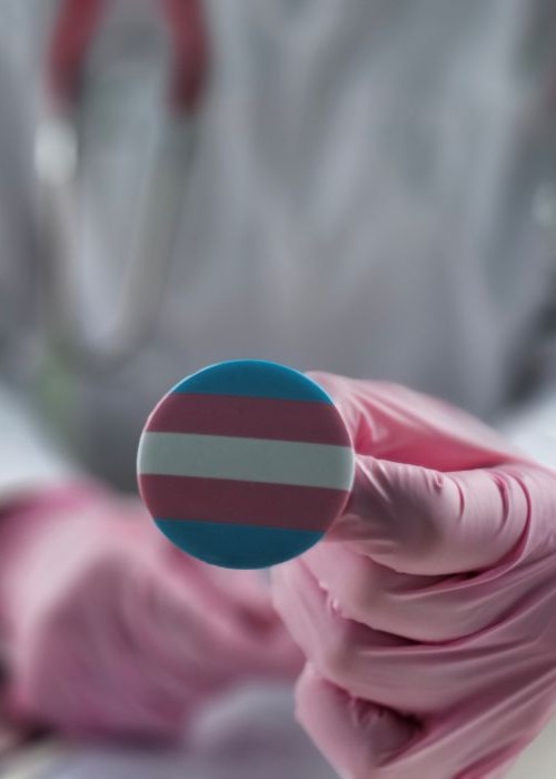 Doctor holding a transgender flag pin