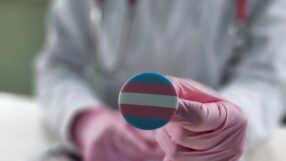 Doctor holding a transgender flag pin