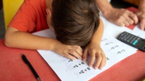 Elementary school student sitting at desk with his head down struggling with math
