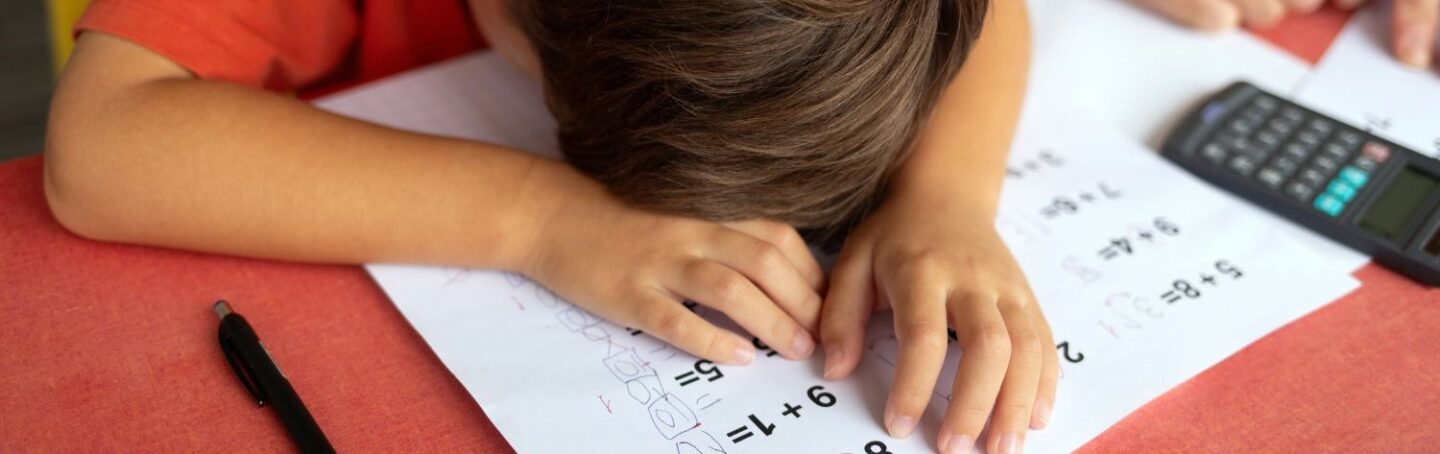 Elementary school student sitting at desk with his head down struggling with math