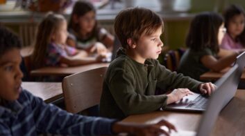 Elementary school students staring at laptops