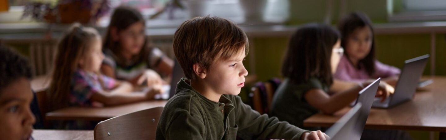 Elementary school students staring at laptops