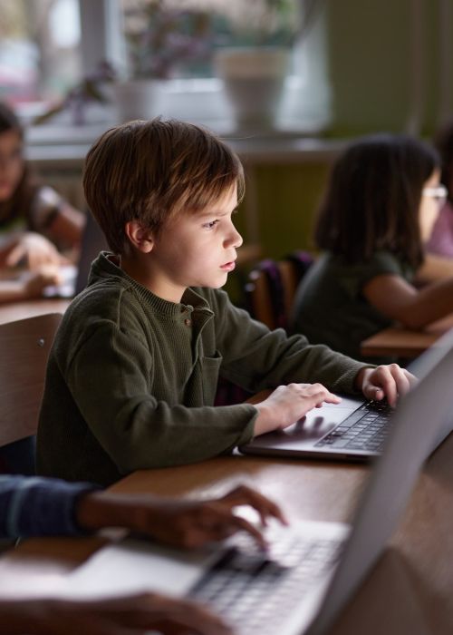 Elementary school students staring at laptops