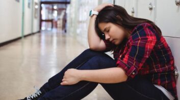 High schooler anxious sitting in the hallway