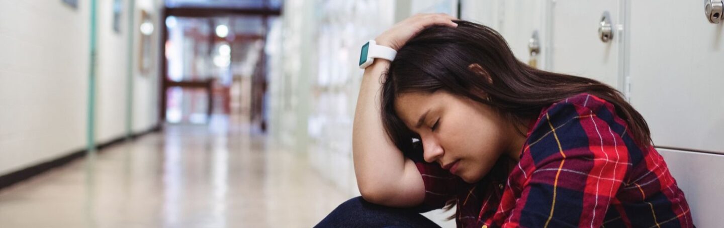 High schooler anxious sitting in the hallway