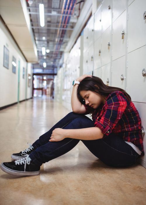 High schooler anxious sitting in the hallway