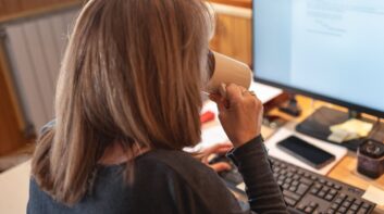 Independent contractor working at a computer and sipping coffee