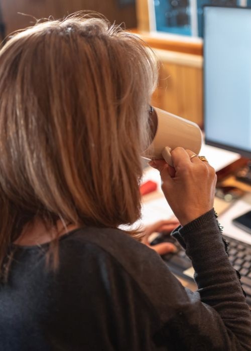 Independent contractor working at a computer and sipping coffee