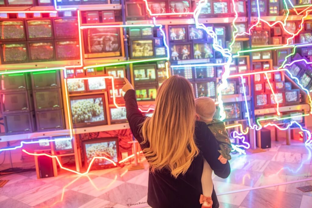 Isabel Brown and Isla in front of a light-up art installation of America
