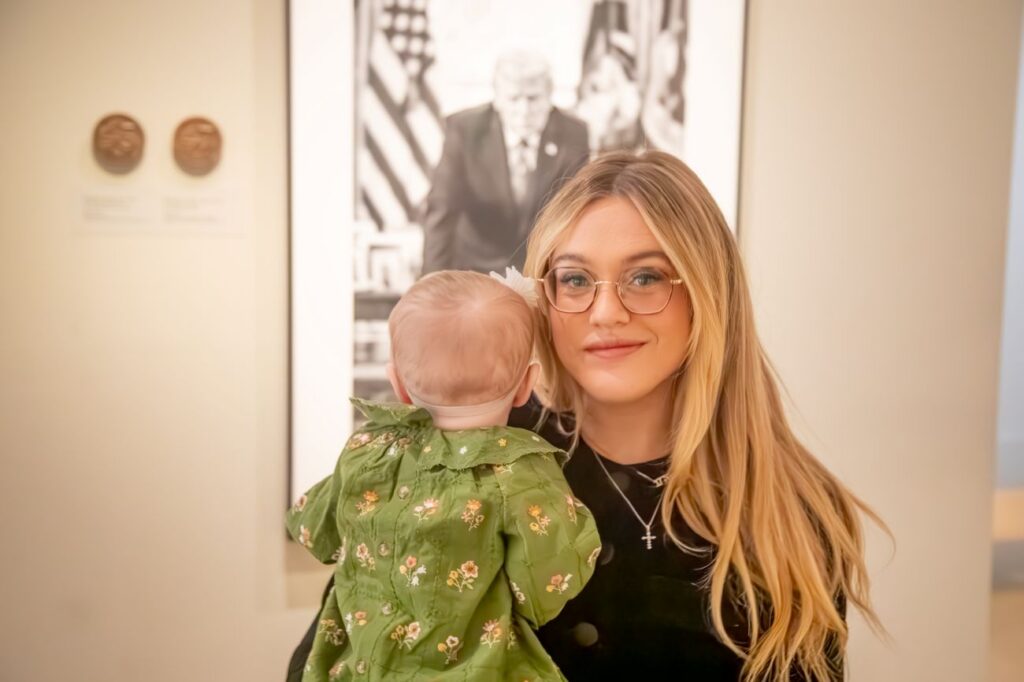 Isabel Brown and Isla in front of Trump portrait