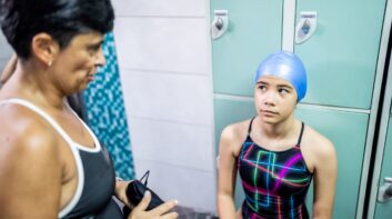 Young girl in swim locker room talking with teacher