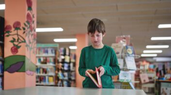 Boy opening a book at a public library