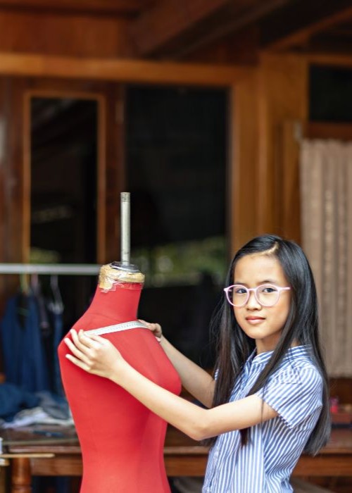 Young female entrepreneur measuring on a dress form