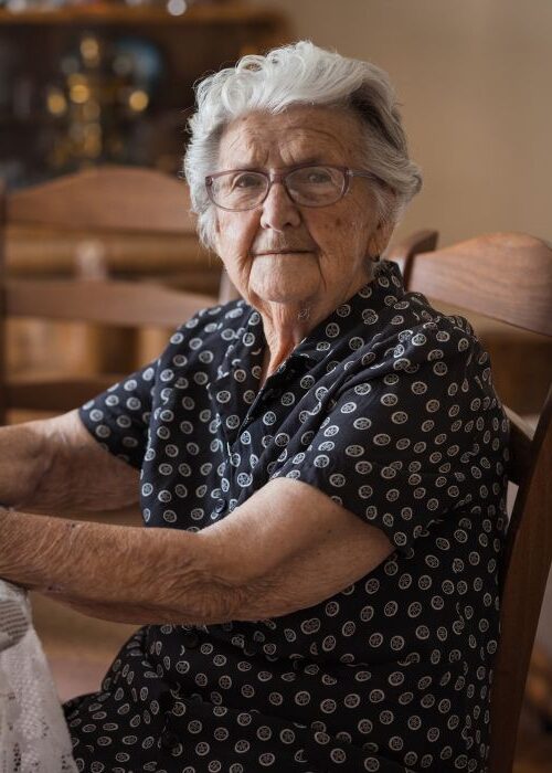 Elderly woman sitting at her kitchen table mobile crop