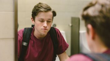 High school boy looking in the bathroom mirror