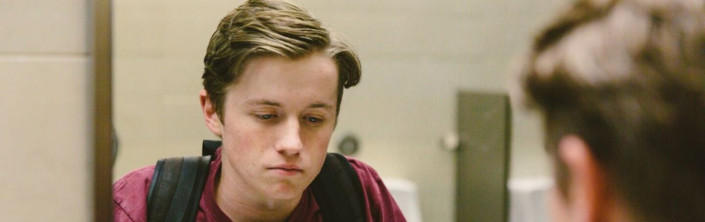 High school boy looking in the bathroom mirror