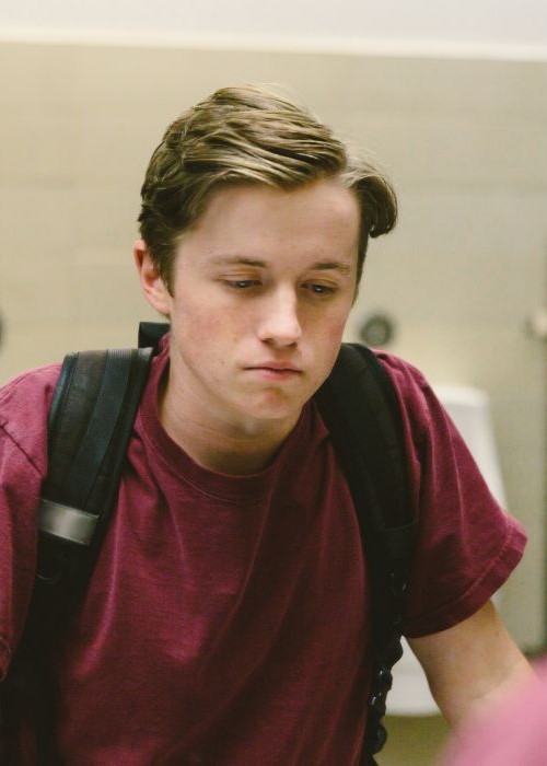 High school boy looking in the bathroom mirror