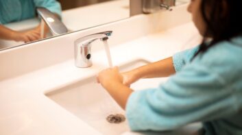 Girl washing her hands in school bathroom