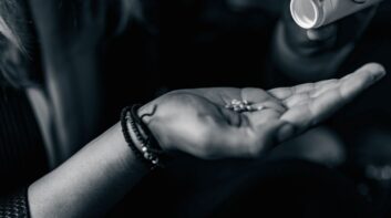 Woman holding pills and pill bottle