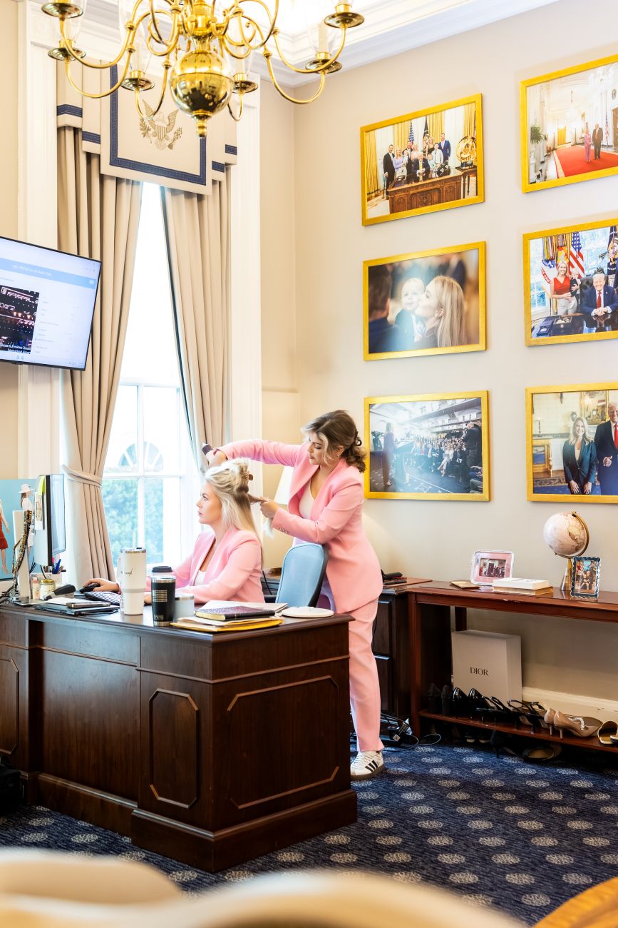 Danielle styling Leavitt's hair while Leavitt works on her computer