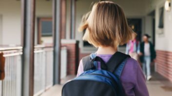 Girl with backpack standing in school hallway