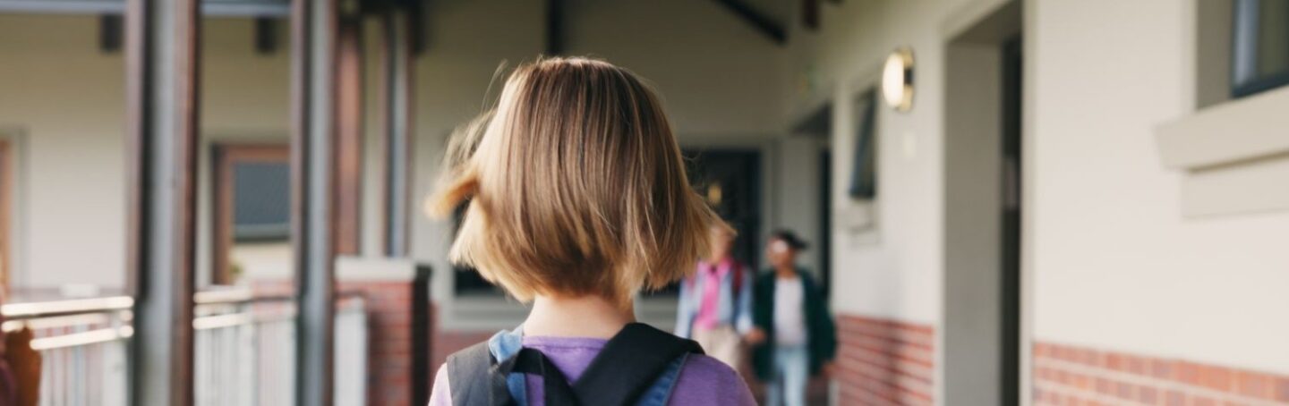 Girl with backpack standing in school hallway
