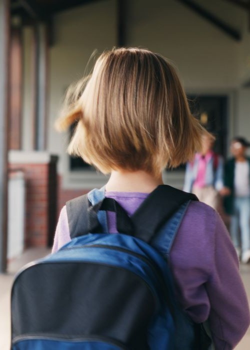 Girl with backpack standing in school hallway