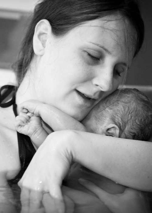 Mother embracing her newborn after home water birth