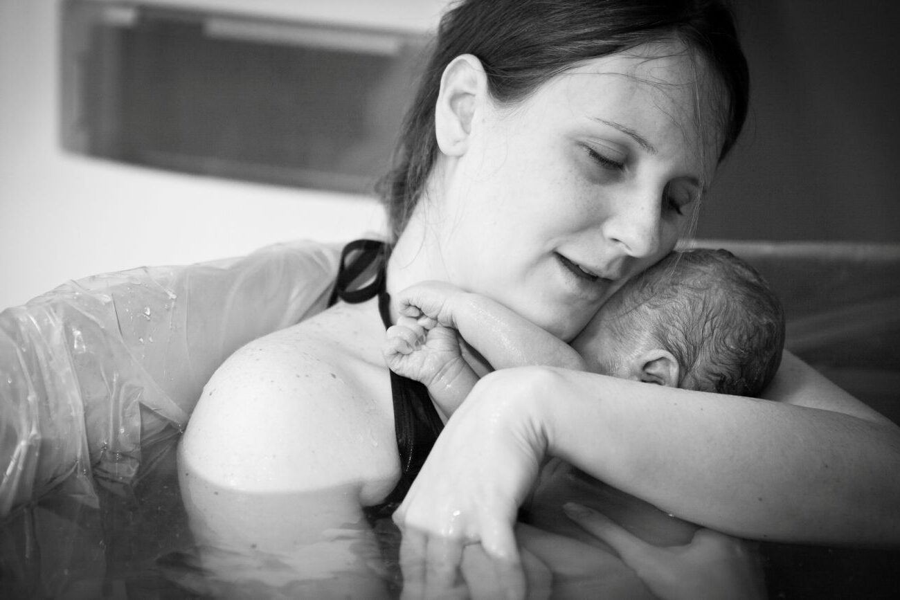 Mother embracing her newborn after home water birth